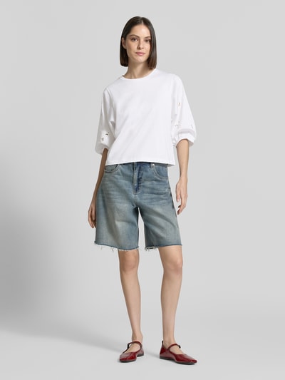 Frauenmodel trägt T-Shirt mit 3/4-Arm und Lochstickerei von Marc Cain aus Reine Baumwolle, Regular-Fit, Rundhalsausschnitt, Rückenlänge 52 cm, Ganzkörperansicht von vorne.