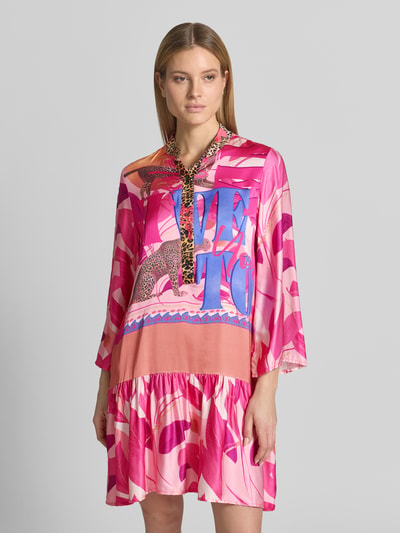 Frauenmodel trägt Relaxed Fit Minikleid aus reiner Viskose mit Animal-Print von miss goodlife, Stehkragen, langärmelig, Knopfleiste, Rosa- und Pinktöne mit abstrakten Formen, glatte Textur, Rückenlänge 100 cm, Brustweite 37 cm, Ärmellänge 58 cm, Ganzkörperansicht von vorne.
