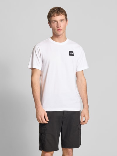 Męski model nosi T-Shirt aus Baumwoll-Mix Modell 'EVOLUTION' von The North Face, biały, krój regular fit, nadruk z logo, długość tyłu w rozmiarze M: 69 cm, całkowity widok z przodu.