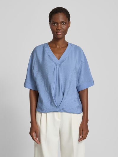 Frauenmodel trägt Blusenshirt mit V-Ausschnitt von Christian Berg Woman in Hellblau, strukturierte Oberfläche, Regular Fit, Halbarm, Ganzkörperansicht von vorne.