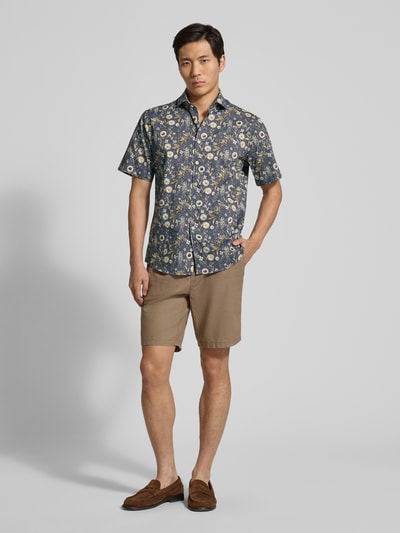 Mężczyzna nosi Modern Fit Freizeithemd im Allover-Look Modell 'Hardy' od Brax, granatowe z kwiatowym wzorem, krótki rękaw, Kent kołnierzyk, długość tyłu 76 cm, szerokość ramion 48 cm, długość rękawa 25 cm, całopostaciowy widok z przodu.