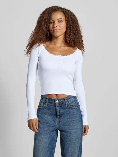Vrouwenmodel draagt wit shirt met lange mouwen van Model 'MAYA' van NOISY MAY®, mix van katoen en elastaan, riblook, met kant, slim fit, knoopsluiting, ruglengte bij maat S: 51 cm, volledige lichaamsvoorzijde.