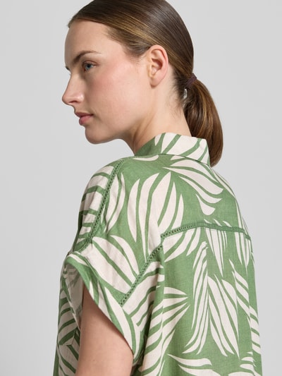 Frauenmodel trägt Bluse aus Viskose-Mix mit Brusttasche von Apricot mit grünem Blattmuster, Hemdblusenkragen, Loose-Fit, Ärmel mit Aufschlag, Ganzkörperansicht Rückansicht. Rückenlänge 65 cm, Ärmellänge 20 cm, Leinen-Viskose-Anteil.