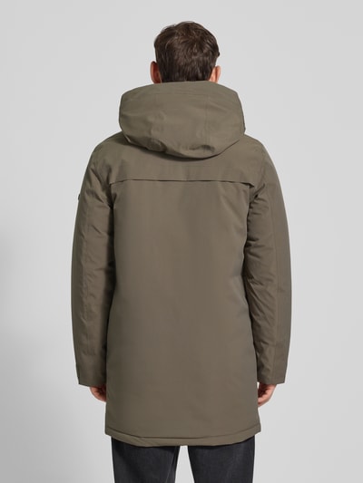 Mężczyzna nosi oliwkowy Parka mit Pattentaschen Modell 'AIDEN' od Didriksons, długość do połowy uda, prosty krój, kaptur, widok całej sylwetki z tyłu. Regular Fit, kieszenie z patkami, paski na rękawach, długość pleców w rozm. M: 92 cm, szerokość ramion: 47 cm, szerokość klatki: 56 cm, długość rękawa: 69 cm.