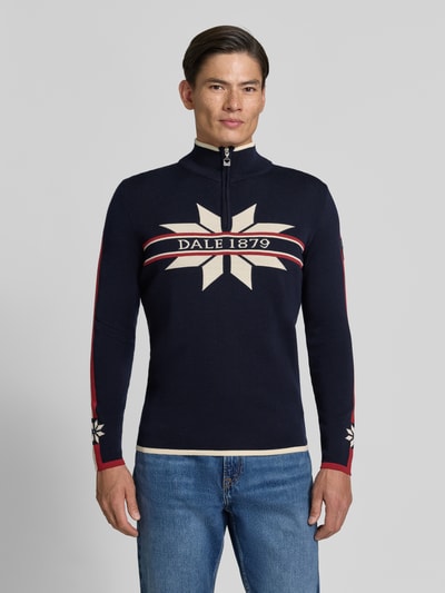 Männermodel trägt Wollpullover mit Label-Print Modell 'Nale' von Dale of Norway in Dunkelblau, Reine Wolle, Ganzkörperansicht von vorne.