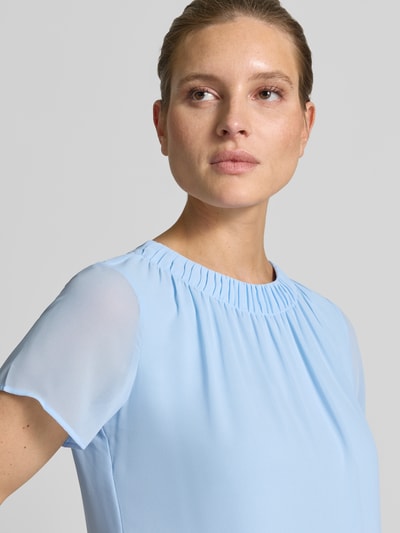 Frauenmodel trägt Loose Fit Blusenshirt aus Chiffon von s.Oliver BLACK LABEL in Hellblau, unifarben, mit Raffungen und Rundhals, Nahaufnahme Oberkörper.