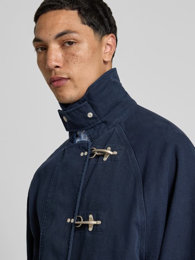 Männermodel trägt Regular Fit Jacke mit Umlegekragen von Forét in Dunkelblau aus Reine Baumwolle, Verschlussschnallen, Nahaufnahme Oberkörper.