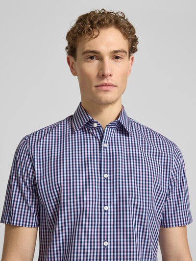 Männermodel trägt Slim Fit Business-Hemd aus katoen met kentkraag van Jake*s, ruitpatroon in blauw, wit en rood, knoopsluiting, 1/2-mouwen, context: heren zakelijk hemd, puur katoen, slim fit, kentkraag, knoopsluiting, 1/2-mouwen, ruglengte maat 39/40 79 cm, schouderbreedte 48 cm, mouwlengte 23 cm, Nahaufnahme Oberkörper