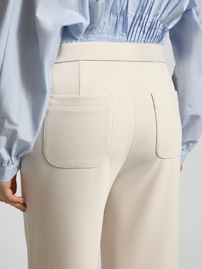 Frauenmodel trägt Hose mit elastischem Bund Modell 'PALINA 6/8 SPORT' von Raffaello Rossi in Creme mit weitem Bein und verkürzter Passform, Nahaufnahme Rückansicht.