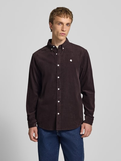 Mężczyzna model nosi Regular Fit Freizeithemd aus Cord mit Button-Down-Kragen od Carhartt Work In Progress w kolorze ciemnobrązowym, bawełna, krój regular fit, wyhaftowane logo, kołnierzyk typu button down, model Madison, długość tyłu w rozmiarze M: 76 cm, szerokość ramion w rozmiarze M: 44 cm, długość rękawów w rozmiarze M: 64 cm, gładka tekstura, matowe wykończenie, całkowity widok z przodu