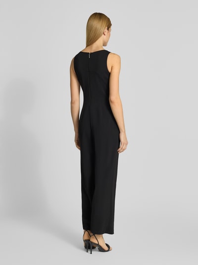 Kobiece model prezentuje kombinezon z okrągłym dekoltem od Calvin Klein Womenswear, krój regular fit, detal z logo, kolor czarny, długość tyłu w rozmiarze S: 140 cm, szerokość w rozmiarze S: 33 cm, całkowita długość w rozmiarze S: 140 cm, długość wewnętrzna nogawki w rozmiarze S: 74 cm, tekstura gładka, widok całej sylwetki z tyłu.