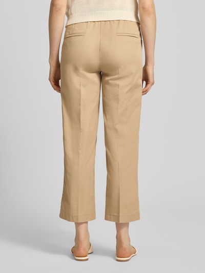 Frauenmodel trägt Wide Fit Stoffhose in 7/8-Länge Modell 'Sue' von TONI im Beige-Ton, Baumwoll-Mix, mit Bügelfalten und Eingrifftaschen, Ganzkörperansicht Rückansicht.