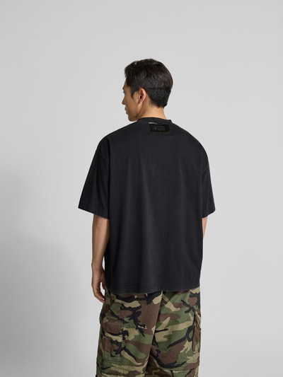 Männermodel trägt T-Shirt aus reiner Baumwolle von VETEMENTS in Schwarz mit Label-Detail, Relaxed-Fit, Kurzärmelig, Rückenansicht.