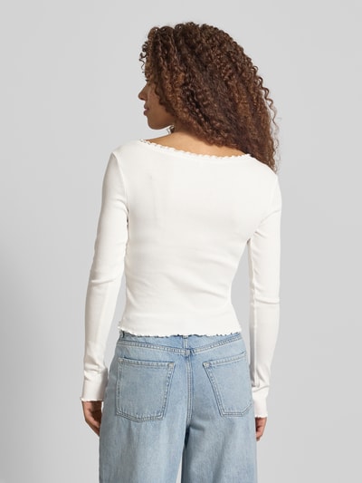 Vrouwenmodel draagt slim fit langarmshirt uit katoenmix model 'LAILA' van Only, effen, cropped, muschelsaum, fijnrib. Volledige achteraanzicht.