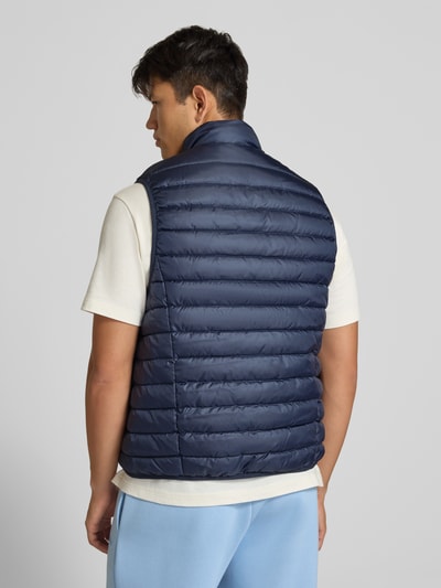 Männermodel trägt Steppweste mit Reißverschlusstaschen Modell 'ELVIS' von JACK & JONES in Dunkelblau, Rückenansicht, Kontext Herrenmode Regular Fit, Stehkragen, Label-Detail, Rückenlänge 67 cm, Schulterbreite 41 cm, Brustweite 54 cm. Ganzkörperansicht Rückansicht.