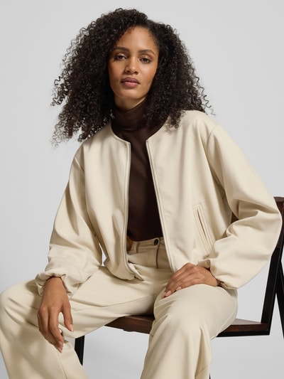 Vrouwenmodel draagt Regular fit damesjack met viscose van FREE/QUENT, elastische materiaalmix, ronde hals, ritssluiting, steekzakken, ballonlook, model 'Nanni', kleur lichtbeige, textuur glad, combinatie van lichte en donkere tinten, close-up bovenlichaam.