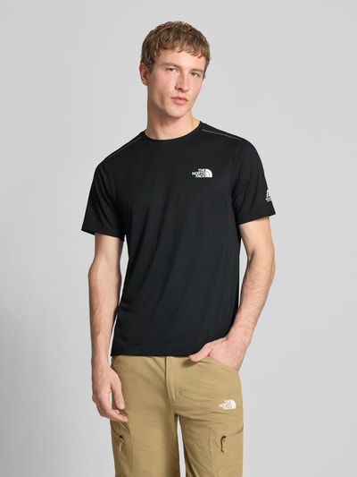 Mannenmodel draagt T-Shirt met Logo en Rundhalsausschnitt van The North Face in zwart, regular fit, borstlogo, voorkant volledige lichaamsweergave. Ruglengte maat M: 69 cm.