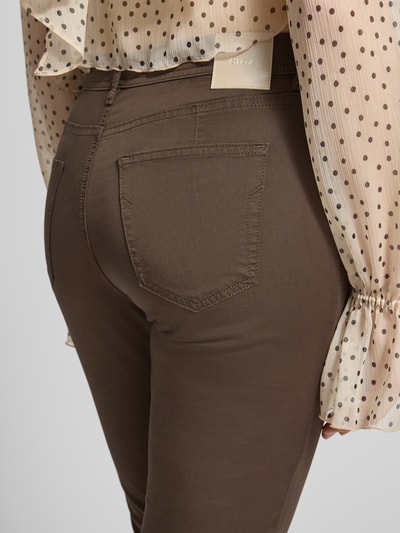 Frauenmodel trägt Hose in verkürzter Passform Modell 'Mary' von Brax aus Baumwoll-Lyocell-Mix mit Eingrifftaschen, Detailaufnahme Rückansicht.