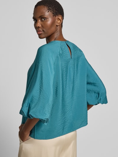 Frauenmodel trägt Regular Fit Bluse aus Viskose-Mix mit 3/4-Arm von Christian Berg Woman in Türkis, leicht glänzende Textur, Ganzkörperansicht Rückansicht. Rückenlänge bei Größe 36: 56 cm, Ärmellänge bei Größe 36: 44 cm, Rundhalsausschnitt.