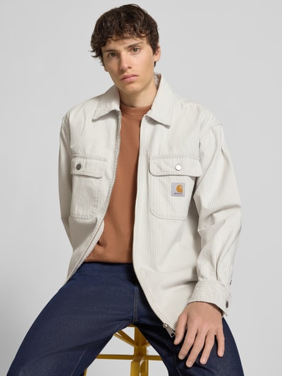 Männermodel trägt Regular Fit Hemdjacke mit Zweiwege-Reißverschluss von Carhartt Work In Progress, Reine Baumwolle, Kentkragen, Brusttaschen, Label-Detail, Rückenlänge bei Größe M 80 cm, Ganzkörperansicht von vorne.