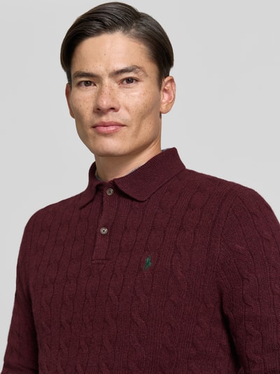 Männermodel trägt Regular Fit Pullover aus Woll-Kaschmir-Mix von Polo Ralph Lauren in Dunkelrot mit Zopfmuster, Nahaufnahme Oberkörper. Herren Pullover von Polo Ralph Lauren