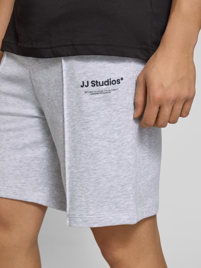 Männermodel trägt Sweatshorts mit Logo Modell 'KANE' von Jack & Jones aus hellgrauem Baumwoll-Mix, Relaxed-Fit, Nahaufnahme Oberschenkel.