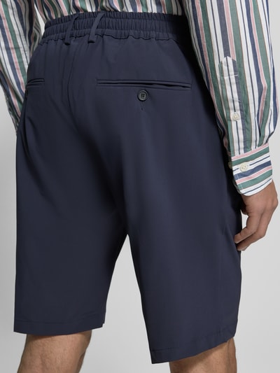 Mężczyznamodel nosi Straight Fit Shorts mit elastischem Bund od CRUNA w kolorze granatowym z kieszeniami z tyłu, szerokość w rozmiarze 50: 42 cm, długość wewnętrzna nogawki 26 cm, całkowity widok z tyłu.
