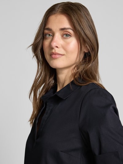 Frauenmodel trägt Hemdblusenkleid mit V-Ausschnitt von ROBE LÉGÈRE, dunkel, glatte Baumwollmix-Struktur, Nahaufnahme Oberkörper.
