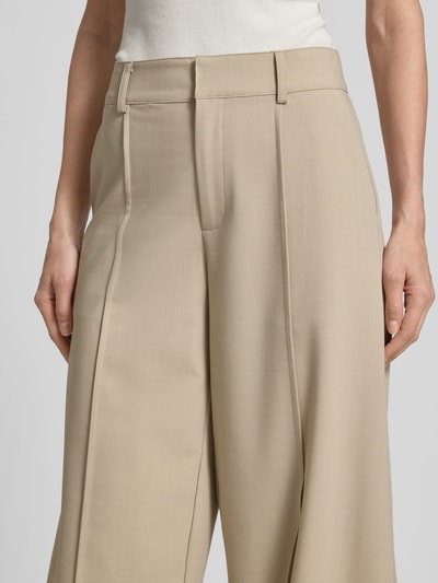 Frauenmodel trägt Barrel Fit Hose mit Längsnähten Modell 'Pija' von mbyM, beige, glatte Textur, Detailaufnahme Bund und Oberschenkel. Material-Mix mit Viskose-Anteil.