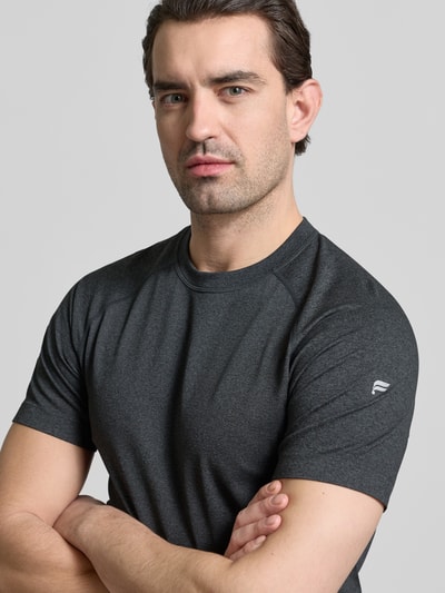 Mężczyznamodel nosi Regular Fit T-Shirt mit Rundhalsausschnitt von Fabletics, ciemnoszary, logo-print, krój regular fit, krótki rękaw, długość tyłu w rozmiarze M: 69 cm. Zbliżenie górnej części ciała.