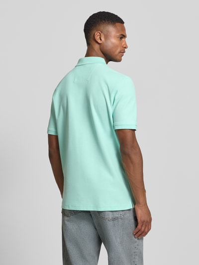 Männermodel trägt Regular Fit Poloshirt mit Logo-Stitching von Fynch-Hatton in Mintgrün, reine Baumwolle, Rückenansicht, Ganzkörperansicht Rückansicht.