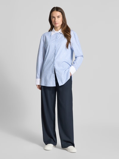 Vrouwenmodel draagt Regular Fit Langarmbluse aus reiner Baumwolle Modell 'ERSENNY' van HUGO, lichtblauw-wit gestreept met overhemdkraag, afgeronde zoom, lange mouwen en knoopsluiting, allover-motief, voorkant afbeelding tot op de voeten.