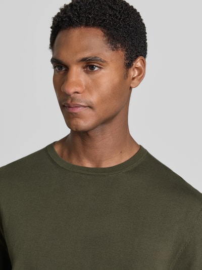 Männermodel trägt Regular Fit T-Shirt aus reiner Baumwolle Modell 'TORINO' von SELECTED HOMME in Olivgrün, unifarben, Nahaufnahme Oberkörper.