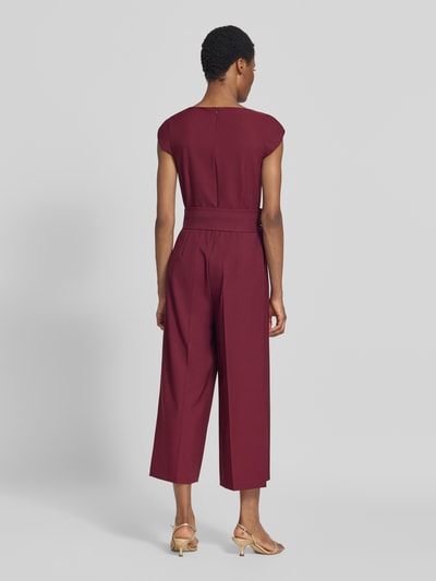 Frauenmodel trägt Regular Fit Jumpsuit mit Bindegürtel von Betty Barclay in Dunkelrot mit fließender Textur, Ganzkörperansicht Rückansicht. Damen Jumpsuit von Betty Barclay.