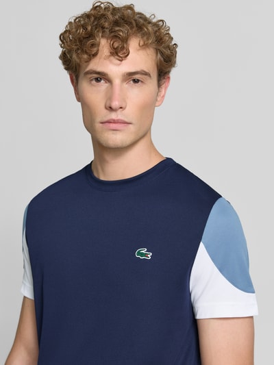 Männermodel trägt Regular Fit Sport-T-Shirt im Colorblock-Design von Lacoste, Herren Sport-T-Shirt, dunkle Blau- und Weißtöne, Nahaufnahme Oberkörper.