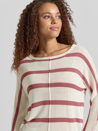 Frauenmodel trägt Boxy Fit Strickpullover aus Viskose-Mix Modell 'ALBERTA' von Pepe Jeans, creme mit rostroten Streifen, Strickoptik, Struktur, Label-Applikation, U-Boot-Ausschnitt, Langarm, gerippter Rumpf- und Ärmelabschluss, Nahaufnahme Oberkörper.