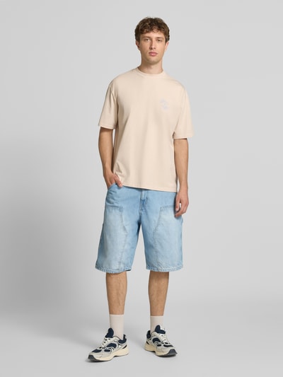 Männermodel trägt Oversized Herren T-Shirt aus Reine Baumwolle mit Label-Print, Modell 'Nuevo' von Pegador, Ganzkörperansicht von vorne. Rückenlänge bei Größe M: 69 cm, Rundhalsausschnitt, T-Shirt in hellem Farbton, strukturierte Textur.