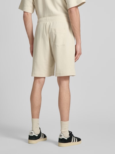 Männermodel trägt Shorts mit Label-Stitching von REVIEW aus Baumwoll-Mix, Regular-Fit, Strukturmuster, Farbe Creme, Ganzkörperansicht Rückansicht.