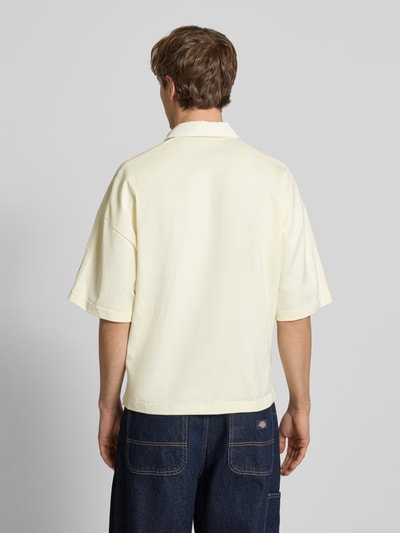 Männermodel trägt Regular Fit T-Shirt mit Polo-Kragen von adidas Originals in Creme, reine Baumwolle, Rückenansicht, Ganzkörperansicht Rückansicht.