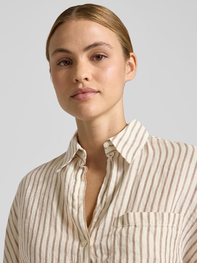 Frauenmodel trägt Relaxed Fit Kurzarmbluse aus reinem Leinen von Marc O'Polo mit gestreiftem Allover-Muster, Nahaufnahme Oberkörper.