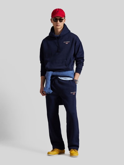 Männermodel trägt dunkelblauen Relaxed Fit Hoodie aus Baumwoll-Mix von Polo Ralph Lauren, unifarben, Kängurutasche, Ganzkörperansicht von vorne.