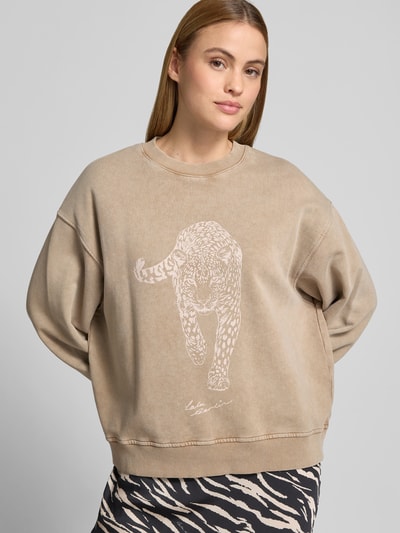 Frauenmodel trägt Oversized Sweatshirt mit Motiv-Print von Lala Berlin in Beige, Reine Baumwolle, Oversized-Fit, Rundhalsausschnitt, elastische Abschlüsse, Rückenlänge bei Größe S 56 cm, Ganzkörperansicht von vorne.