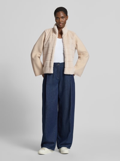 Frauenmodel trägt Jacke mit Viskose-Anteil Modell 'BALIA' von EMME in Beige mit Stehkragen, Kunstfellbesatz und Steppnähten, Ganzkörperansicht von vorne.