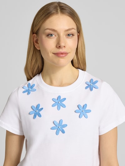 Kobiece modelka nosi T-Shirt mit Stitchings und Perlen od Rich & Royal, damski t-shirt z bawełny, krój regular fit, hafty, perły, okrągły dekolt, długość tyłu w rozmiarze S: 54 cm, zbliżenie na górną część ciała.