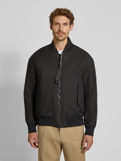 Männermodel trägt zwarte regular fit Heren jack van katoenmix met opstaande kraag, mouwzak, steekzakken, elastische boorden. Ganzkörperansicht van voren. Regular Fit Jacke aus Baumwoll-Mix Modell 'Pulse' van g-lab, Ruglengte maat M: 70 cm, Schouderbreedte: 55 cm, Borstwijdte: 50 cm, Mouwlengte: 61 cm.