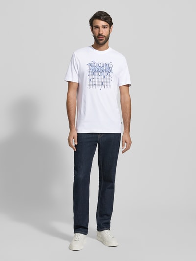 Männermodel draagt Regular Fit T-Shirt aus reiner Baumwolle Modell 'THOMPSON' van BOSS, wit met labelprint, korte mouw, unikleur, ganzkörperansicht von vorne.