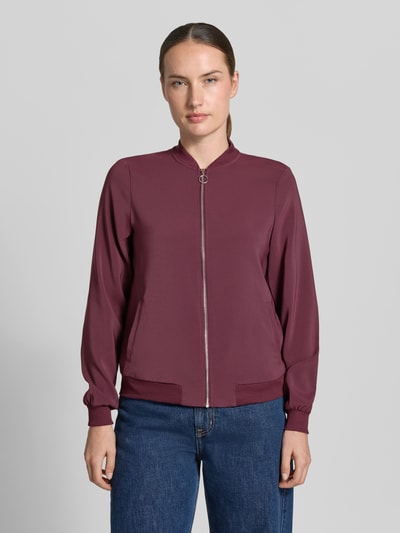 Frauenmodel trägt Regular Fit Blouson mit Reißverschluss-Detail von VERO MODA, dunkles Beerenrot, glatte Textur, Ganzkörperansicht von vorne. Damen Bomberjacke / Blouson.