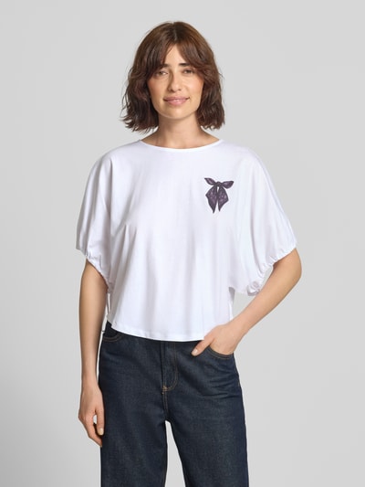 Frauenmodel trägt T-Shirt mit Motiv-Print und Kordelzug am Ärmel von Rich & Royal, weiße Baumwolle, lockerer Schnitt, Ganzkörperansicht von vorne.