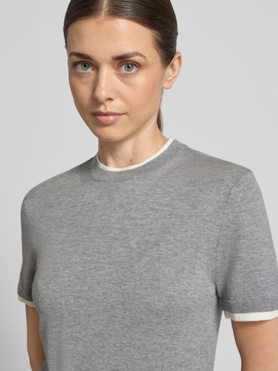 Modelka kobieca nosi Strickshirt aus Leinen-Mix in Two-Tone-Machart od Stefanel, mieszanka lnu z dodatkiem kaszmiru, krój slim fit, dwa kolory, okrągły dekolt, długość tyłu w rozmiarze S: 54 cm, długość rękawów w rozmiarze S: 20 cm, szara faktura, zbliżenie górnej części ciała