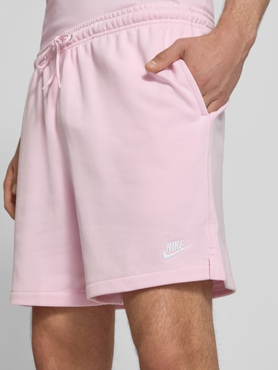 Männermodel trägt Shorts mit Label-Stitching und elastischem Bund von Nike aus Baumwoll-Mix in Rosa, Relaxed-Fit, Nahaufnahme Oberschenkel.
